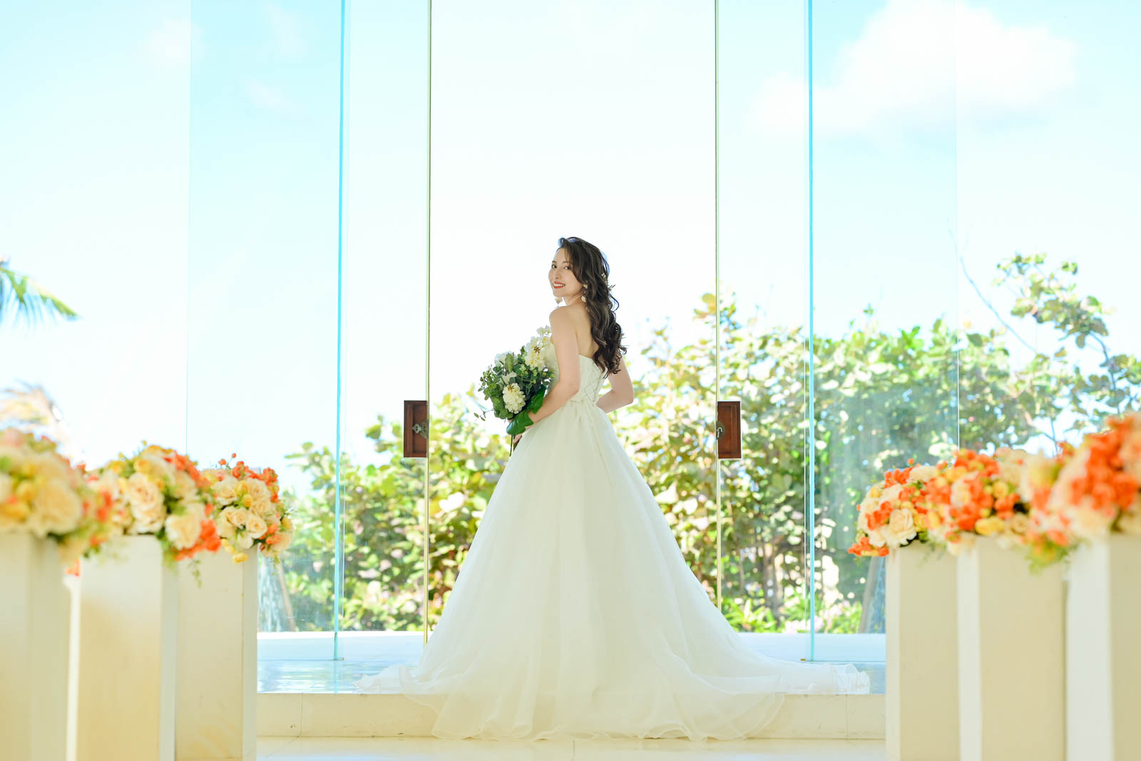 チャペルのガラス扉前でブーケを持つ花嫁の後ろ姿