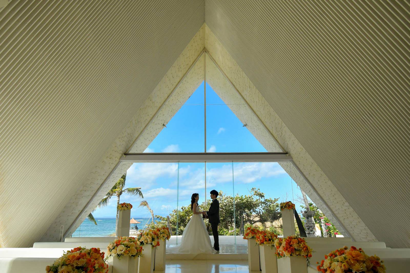 チャペル祭壇越しに海を背景に立つ新郎新婦のシルエット