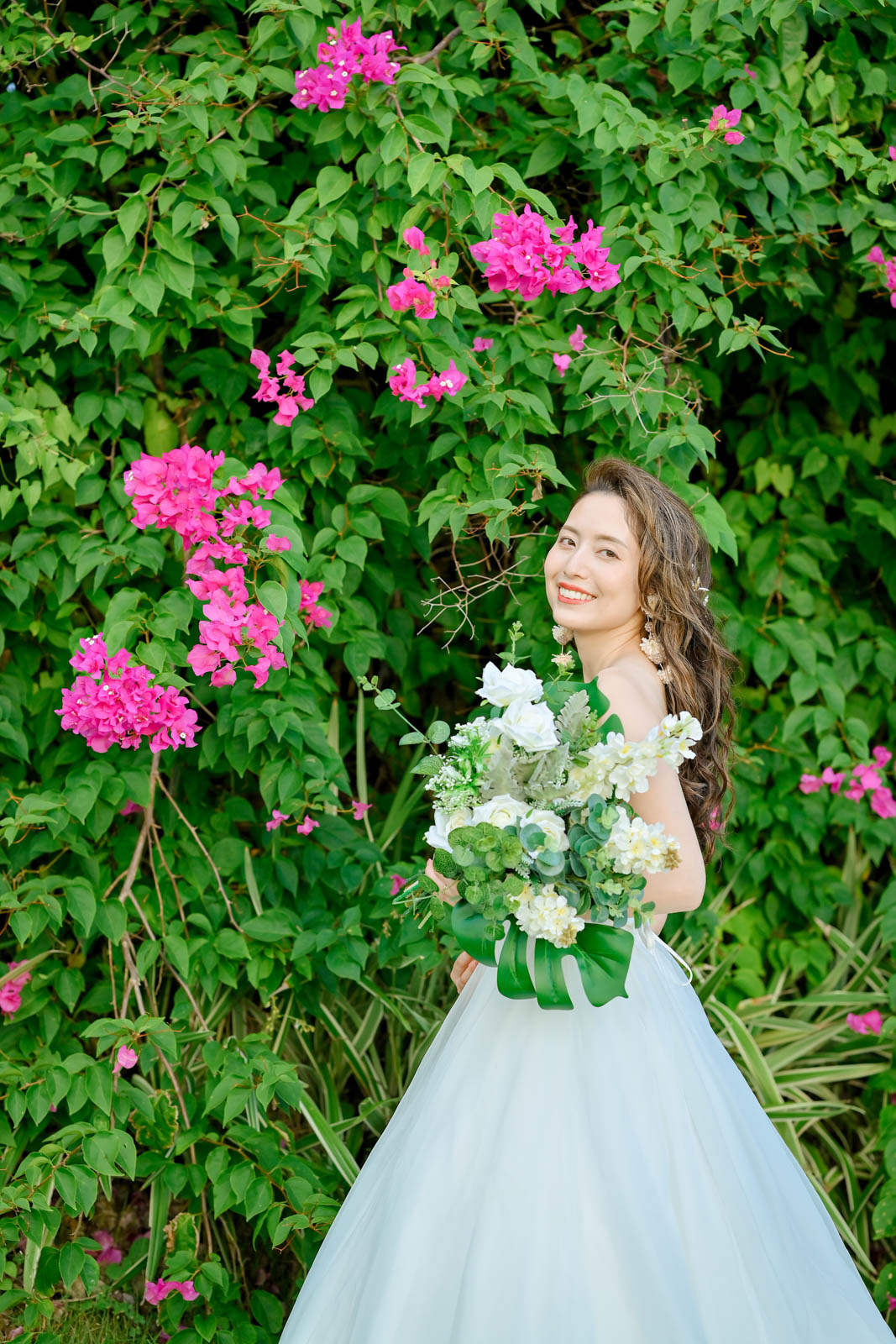 ブーゲンビリアの花の前で笑顔を見せる花嫁｜インターコンチネンタル・バリ・リゾート