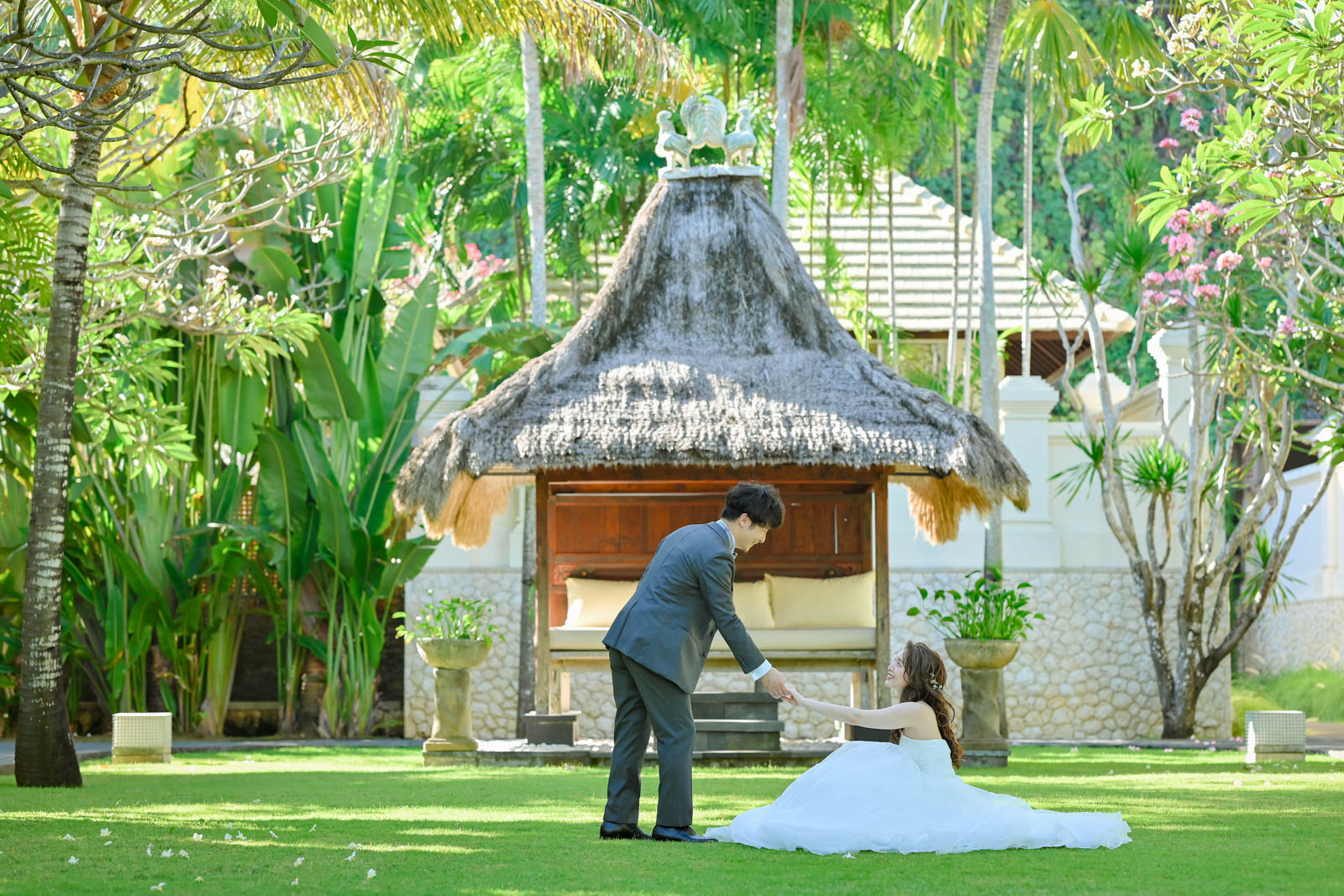 緑に囲まれたガーデンで新郎が座る新婦の手を取るシーン｜インターコンチネンタル・バリ・リゾートでのフォトウェディング