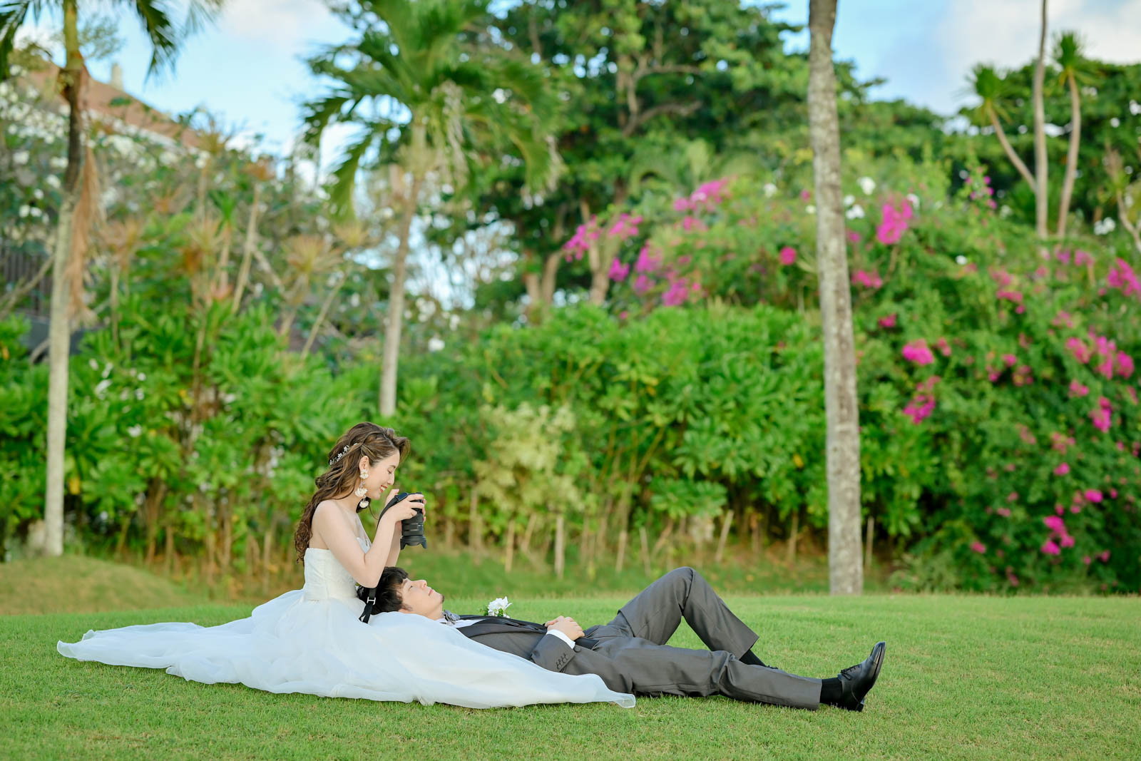 ガーデンの芝生に寝転び、カメラを向ける花嫁と笑顔の新郎｜インターコンチネンタル・バリ・リゾート