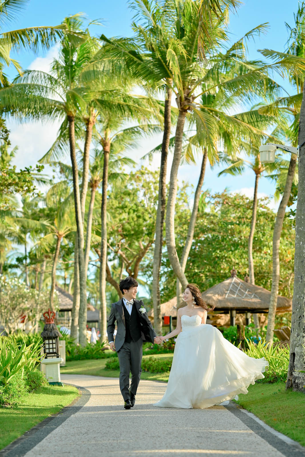南国の並木道を手を取り合って歩く新郎新婦｜インターコンチネンタル・バリ・リゾート