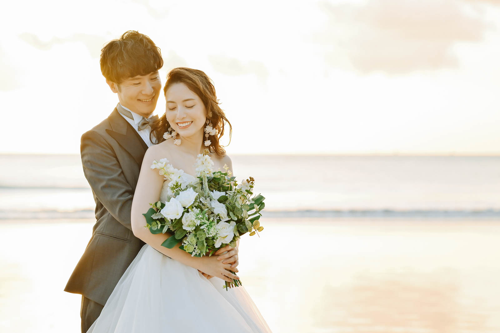 夕暮れの海を背景に抱きしめ合う新郎新婦｜ジンバランビーチのサンセットフォト