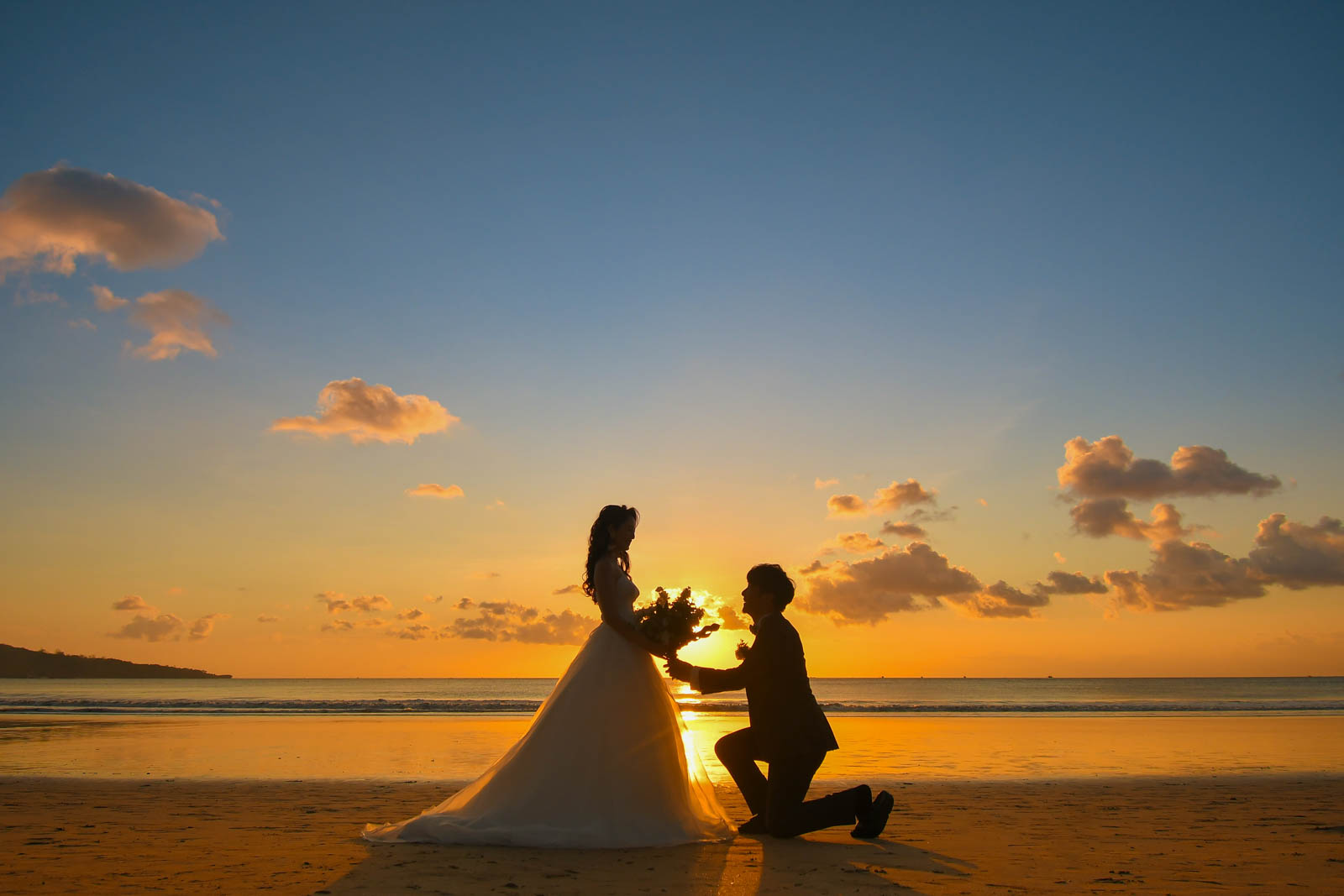 サンセットビーチでひざまずきプロポーズする新郎と花嫁のシルエット｜ジンバランフォトウェディング