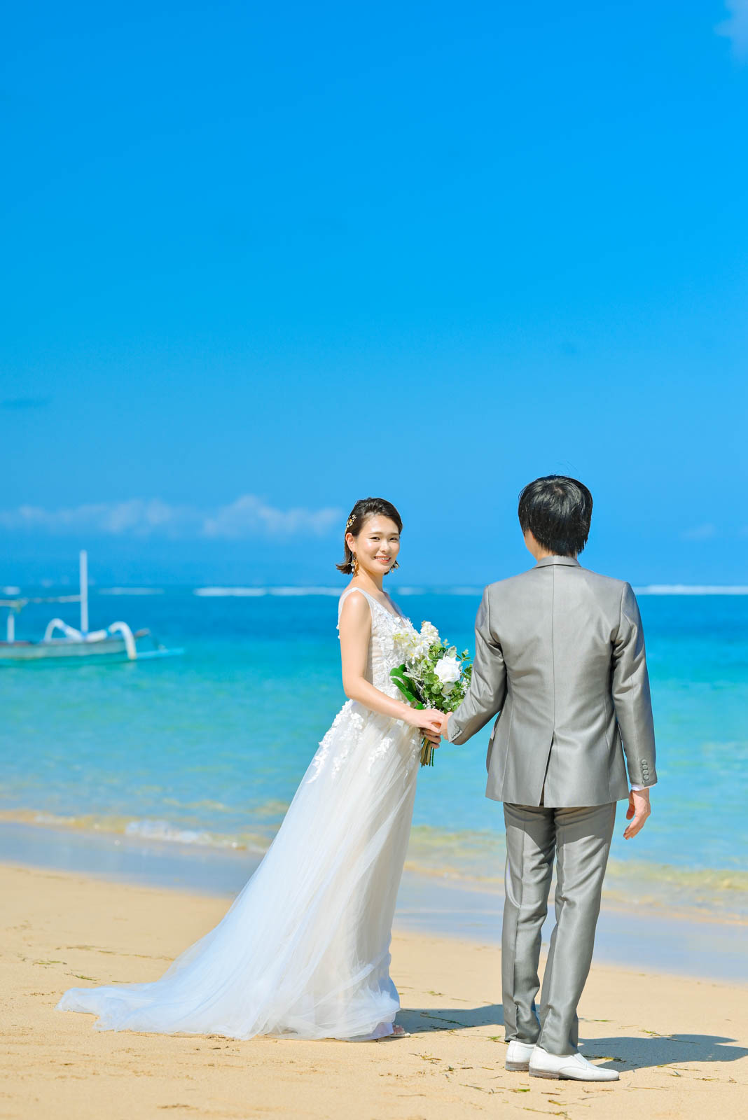 透き通る海をバックに並んで立つ新郎新婦のビーチフォト。穏やかな表情とロケーションが映える一枚