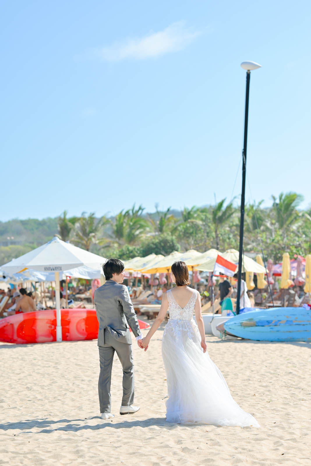 バリ島のビーチを手をつないで歩く新郎新婦の後ろ姿。海沿いの自然な雰囲気を残したビーチフォト
