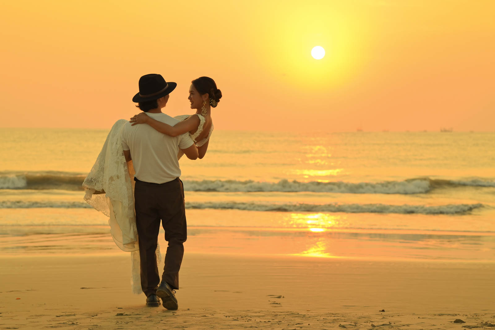 夕暮れのジンバランビーチを手をつないで歩く新郎新婦